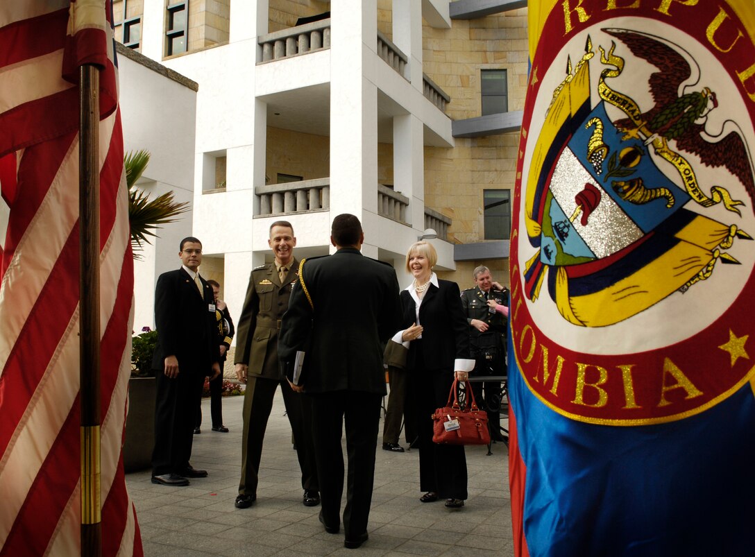 Behind the Colombian and U.S. flags, an Army attache officer greets Chairman of the Joint Chiefs of Staff U.S. Marine Corps Gen. Peter Pace, and his wife Lynne, at the American embassy in Bogota, Colombia, Jan. 19, 2007. 