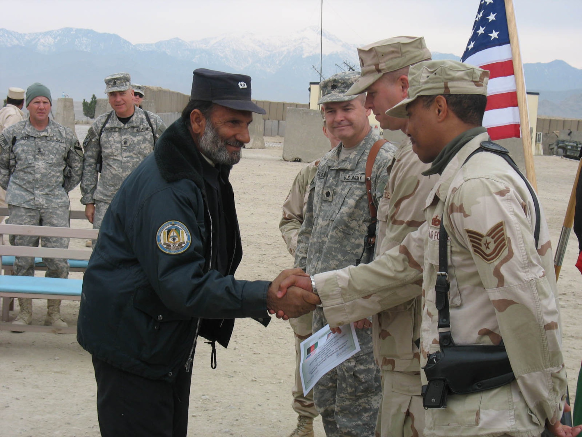 FORWARD OPERATING BASE MEHTAR LAM, Afghanistan -- An Afghan National Police officer shakes hands with Air Force Tech. Sgt. James Shelton, Mehtar Lam Provincial Reconstruction Team Police Training and Assessment Team instructor, prior to receiving his training certificate during the PTAT law enforcement course graduation ceremony Jan. 19.  A group of nine officers went through the weeklong course to learn about police tactics, procedures and professionalism.  (U.S. Air Force Photo/Capt. Gerardo Gonzalez)