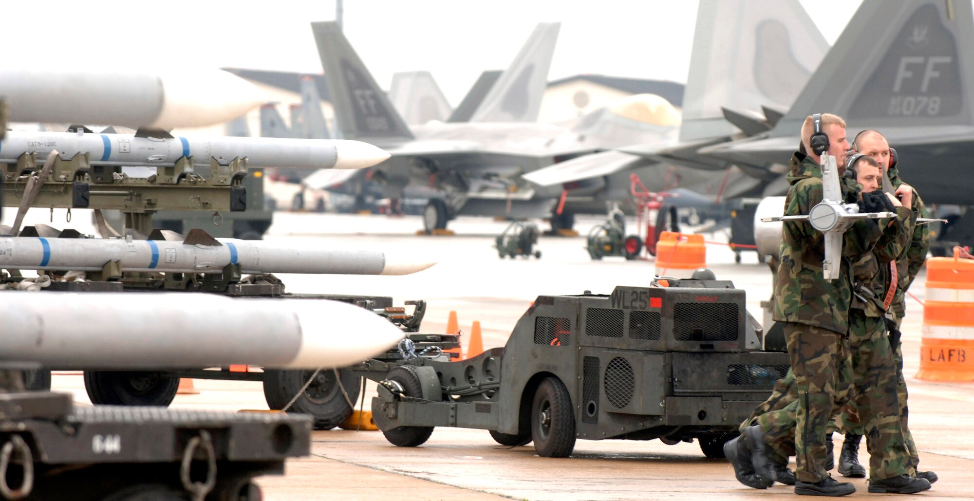 Staff Sgt. Andre Rice, Senior Airman Patrick Webb, and Senior Airman Scott McCans prepare to load a missile on an aircraft during the annual Load Competition Jan. 18 at Langley Air Force Base, Va. The competition evaluates technical proficiency, safety procedures and overall time. (U.S. Air Force photo/Airman 1st Class Vernon Young) 