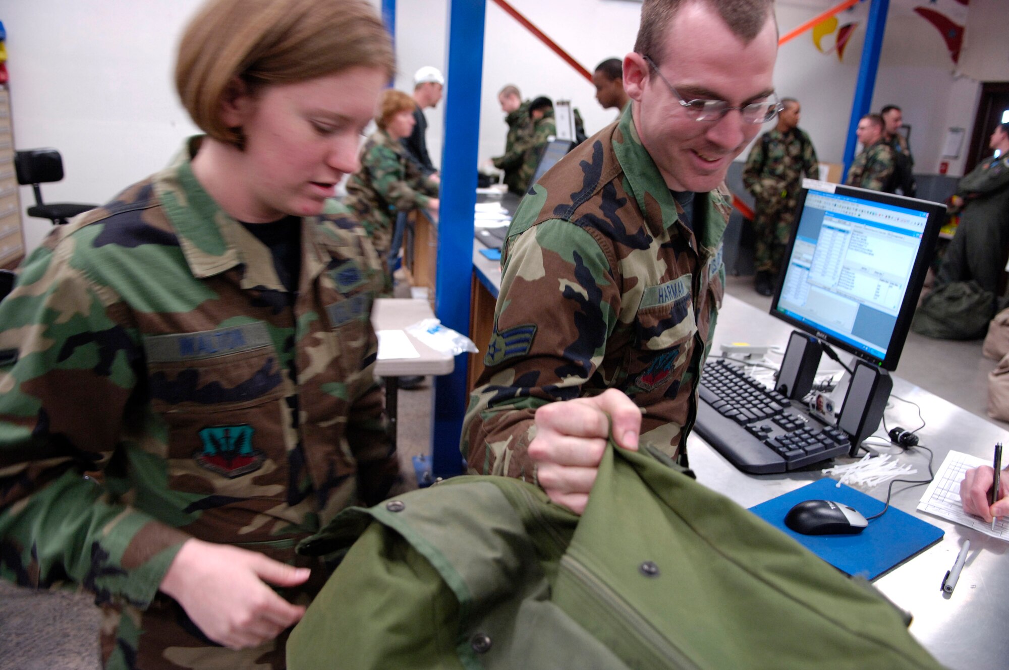 Airman Stephanie Walton and Senior Airman William Harman quickly issue equipment to Airmen as they receive mobility gear during Exercise Bushwacker 07-02 Jan. 20 at Davis-Monthan Air Force Base, Ariz. Bushwacker 07-02 is an operational readiness exercise that tests a wing's deploy abilities. Both Airmen are assigned to the 355th Logistic Readiness Squadron. (U.S. Air Force photo/Senior Airman Jesse Shipps)
