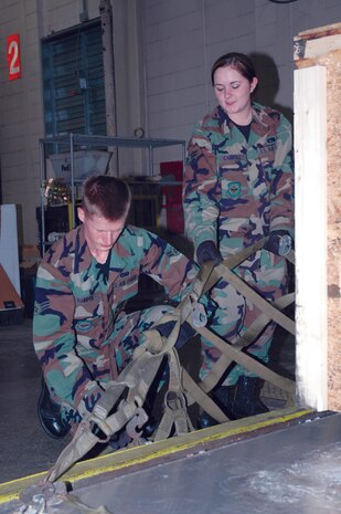 Airmen 1st Class Stephen Harper and Stacia Carroll, 437th Aerial Port Squadron air transportation specialists, secure a  net to the side of a cargo pallet at the 437 APS warehouse Tuesday. (U.S. Air Force photo by Airman 1st Class Dani Pacheco)