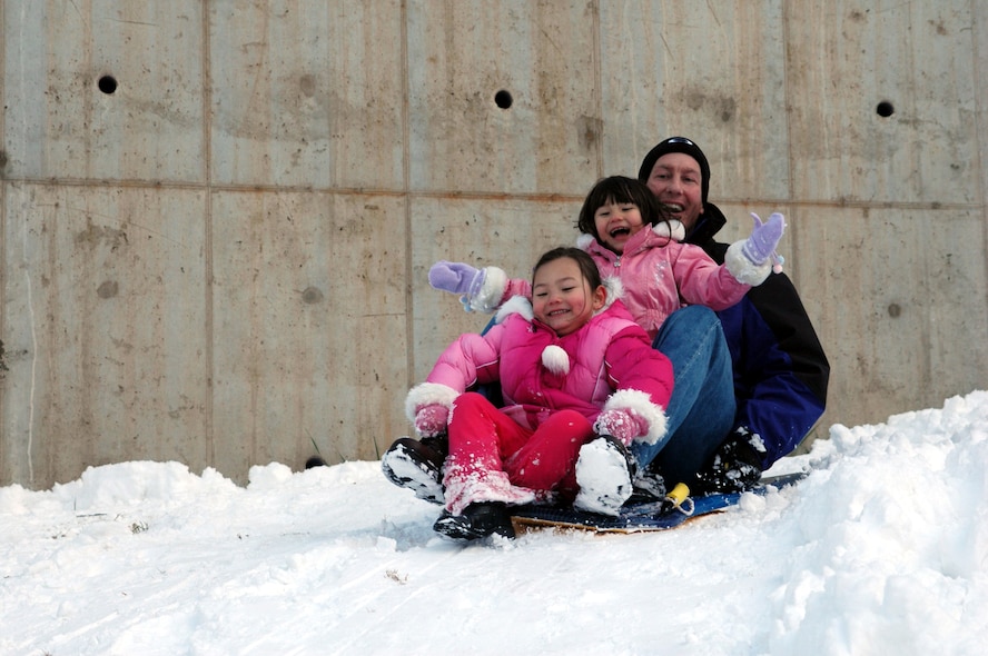OSAN AIR BASE, Republic of Korea --  Lt. Col. Daren Sears and daughters Tara, 5, and Brooke, 3, enjoy a day of sledding on a hill near Seoraksan Tower 211 Sunday following Saturday's late night snowstorm which covered the base with 6.25 inches of snow. The region receives an average of 15 inches of snow between December and March. (U.S. Air Force photo by Tech. Sgt. Michael O'Connor)