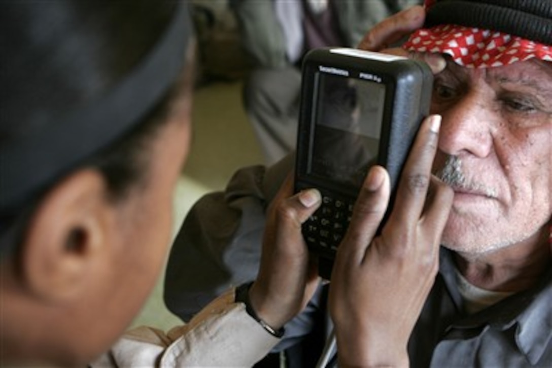 U.S. Marine Corps Sgt. A.C. Wilson uses a retina scanner to positively identify a member of the Baghdaddi city council prior to a meeting with local tribal figureheads, sheiks, community leaders and U.S. service members deployed with Regimental Combat Team-7 in Baghdaddi, Iraq, on Jan. 10, 2007.  Wilson is attached to the 4th Civil Affairs Group.  