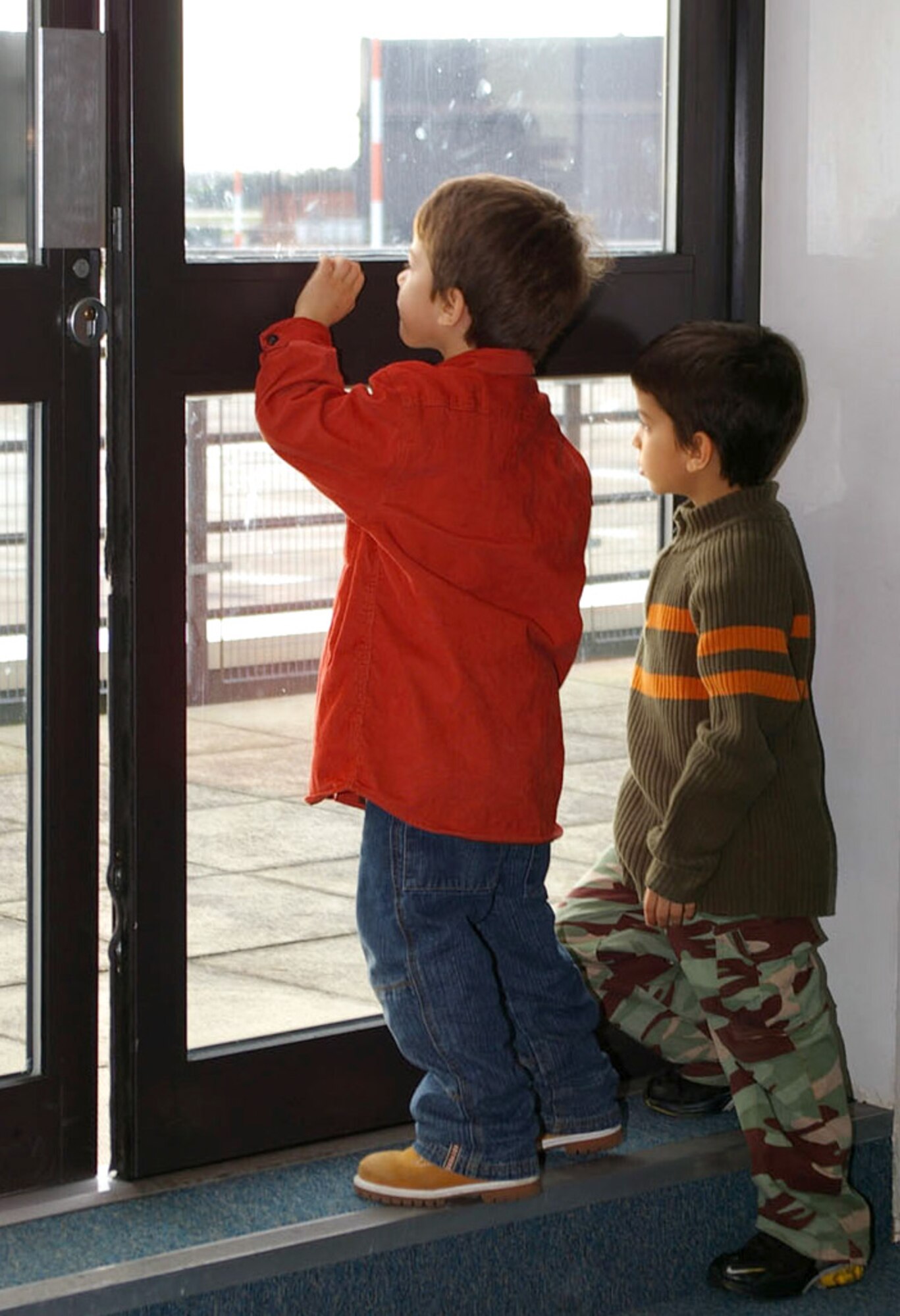 Elijah Cardenas, 5, and his brother Andr?, 7, gaze out onto the runway Jan. 23 at Royal Air Force Mildenhall, England. They watch the plane outside being prepared for the deployment that their father, Senior Airman Miguel Cardenas, is preparing to leave on, to Southwest Asia. Airman Cardenas is assigned to the 100th Civil Engineer Squadron. (U.S. Air Force photo/Karen Abeyasekere)
