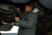 MINOT AIR FORCE BASE, N.D. -- Robert Aguilar, B-52 project manager from Edwards Air Force Base, Calif., adjusts a cord on the engine of a B-52H Stratofortress Jan 19. The cord is attached to an instrument control panel which will measure the differences in engine performance between the use of JP-8 fuel, which the B-52 is accustom to, verses the new Fischer-Tropsch, a synthetic fuel. The testing of synthetic fuel in cold weather is the last step in the certification process to help reduce Air Force dependence on imported fuel.  (U.S. Air Force photo by Airman 1st Class Joe Rivera) 