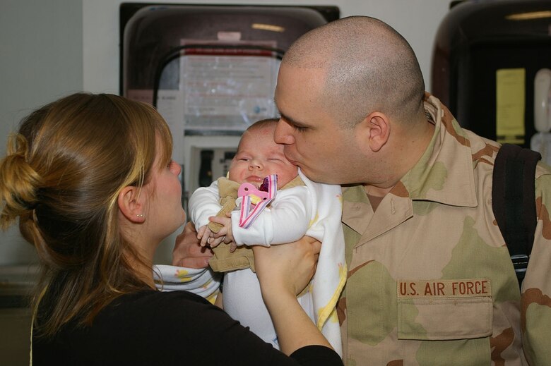 Senior Airman Michael Rios, 100th Civil Engineer Squadron, kisses his 7-week-old daughter, Alleigh, and wife, Cristy, a kiss goodbye at the passenger terminal Tuesday before leaving on a deployment to Southwest Asia. (U.S. Air Force photo by Karen Abeyasekere)

