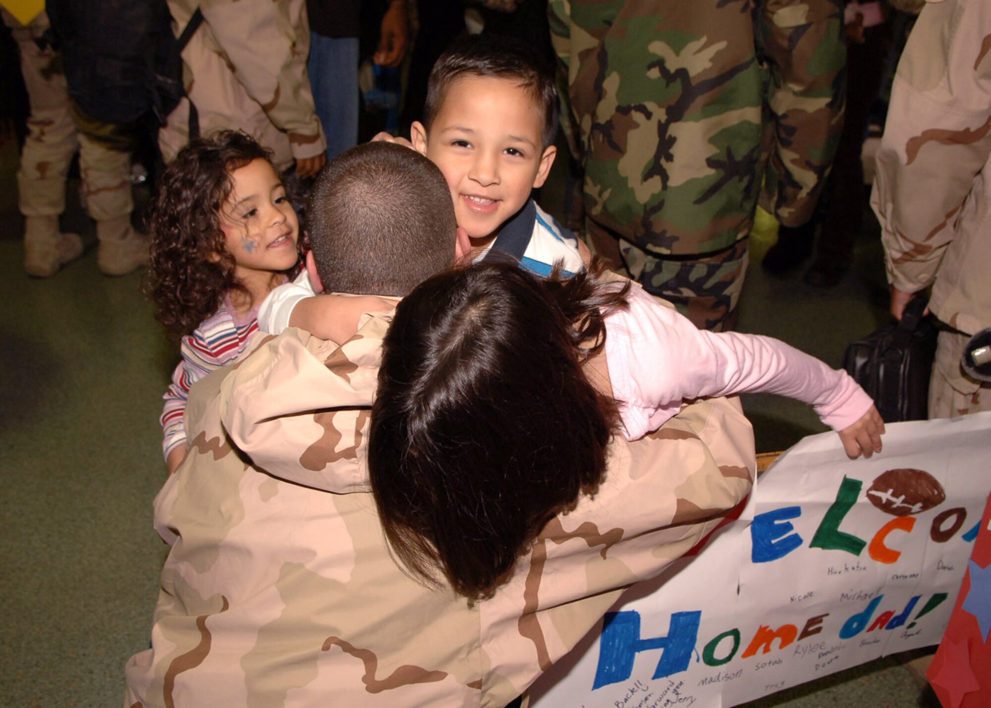 Tech. Sgt. Philip Ramirez hugs his children Gabriella, 4, Philip, 6, and Alyssa, 8, after returning Jan. 23 from his deployment to Southwest Asia. Sergeant Ramirez is assigned to the 374th Comptroller Squadron at Yokota Air Base, Japan. (U.S. Air Force photo/Senior Airman Veronica Pierce) 
