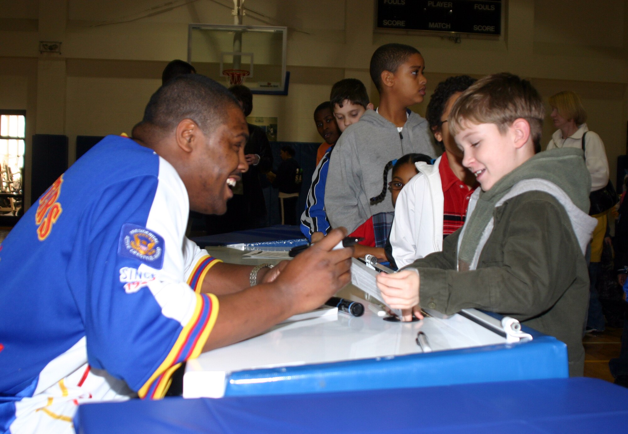 Harlem Globetrotter Otis Key signs an autograph Jan. 22 for Madrigal Youth Center School Age program member Hunter McCracken. Mr. Key spent the evening signing autographs and meeting Team Sheppard members. (U.S. Air Force photo/Airman 1st Class Jacob Corbin.)