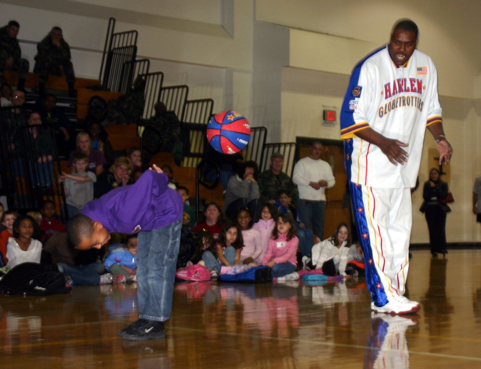 Harlem Globetrotter Otis Key teaches a basketball trick Jan. 22 to Michael Harris, a participant in the Madrigal Youth Center's School Age program, at the Pitsenbarger Fitness Center. Mr. Key spent the evening signing autographs and meeting Team Sheppard members. (U.S. Air Force photo/Airman 1st Class Jacob Corbin.)