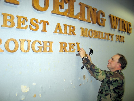 Master Sgt. Mark Bergeron, 92nd Air Refueling Wing command superintendent, removes wall lettering in the White House Tuesday. This is one of many steps in the wing headquarter building?s makeover, which started in November and is scheduled for completion in mid-August. (U.S. Air Force photo by Staff Sgt. Connie L. Bias)