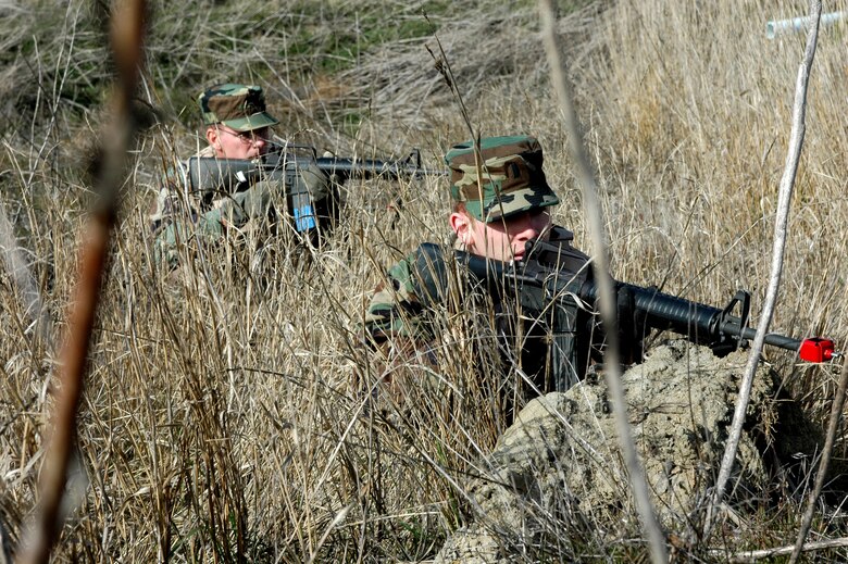 1st Lt. Michael Johnson, (foreground), 21st Airlift Squadron, and Col. Stephen Shea, (background), 60th Mission Support Group commander, take cover as they battle “insurgents” during the field exercise portion of the Combat Skills Training course. The two-day course is designed to teach Travis Airmen basic combat survival skills. (U.S. Air Force photo by Staff Sgt. Candy Knight)