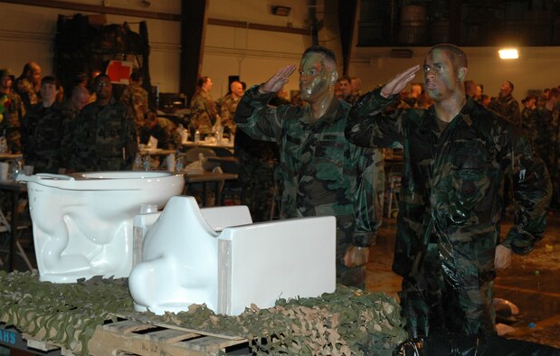 OSAN AIR BASE, Republic of Korea --  Army Sgt. Bernard Aquino, 3rd Battlefield Coordination Detachment, left, and Airman 1st Class Christopher Russell, 51st Civil Engineer Squadron, salute the President of the Mess following their trip to the ‘grog.’ Both had to navigate their way through an obstacle course while being pummeled by water balloons and super soakers. The Osan 5/6 Club hosted the first Team Osan 'Enlisted Only' Combat Dining-In Saturday at the traffic management office warehouse in Bldg 635. (U.S. Air Force photo by Tech. Sgt. Michael O'Connor)