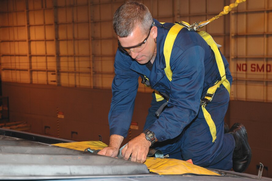 Tech. Sgt. Mark Harrell, 919th Maintenance Squadron aircraft inspector, wears a safety harness attached to an overhead fall restraint as he secures straps on the life rafts  of an MC-130 Combat Talon I aircraft on Duke Field, Fla. Sergeant Harrell, completes this inspection monthly in preparation for an upcoming annual safety inspection that will be held Feb. 12-16. (U.S. Air Force Photo/Senior Airman Erik Hofmeyer)