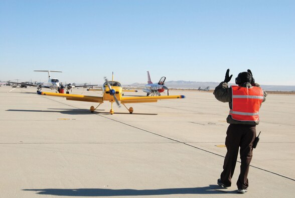 Miguel Avina, 412th Maintenance Squadron transportation alert crash recovery specialist, guides a privately-owned aircraft taxiing on Edwards’ flightline Jan. 20, 2007. The aircraft was flown by Marion Nauman, chairperson for the Ventura Chapter of Ninety-Nines, Inc. as part of the Ninety-Nines’ fly-in here. The organization attended the Air Force Flight Test Center’s safety briefing. (Photo by Airman 1st Class Julius Delos Reyes)