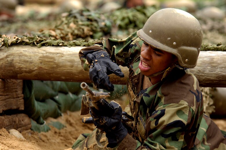 Inching his way through an obstacle, an Airman struggles to keep his imitation M-16 out of the dirt lest he face the wrath of one of the field instructors, who watch his every move.