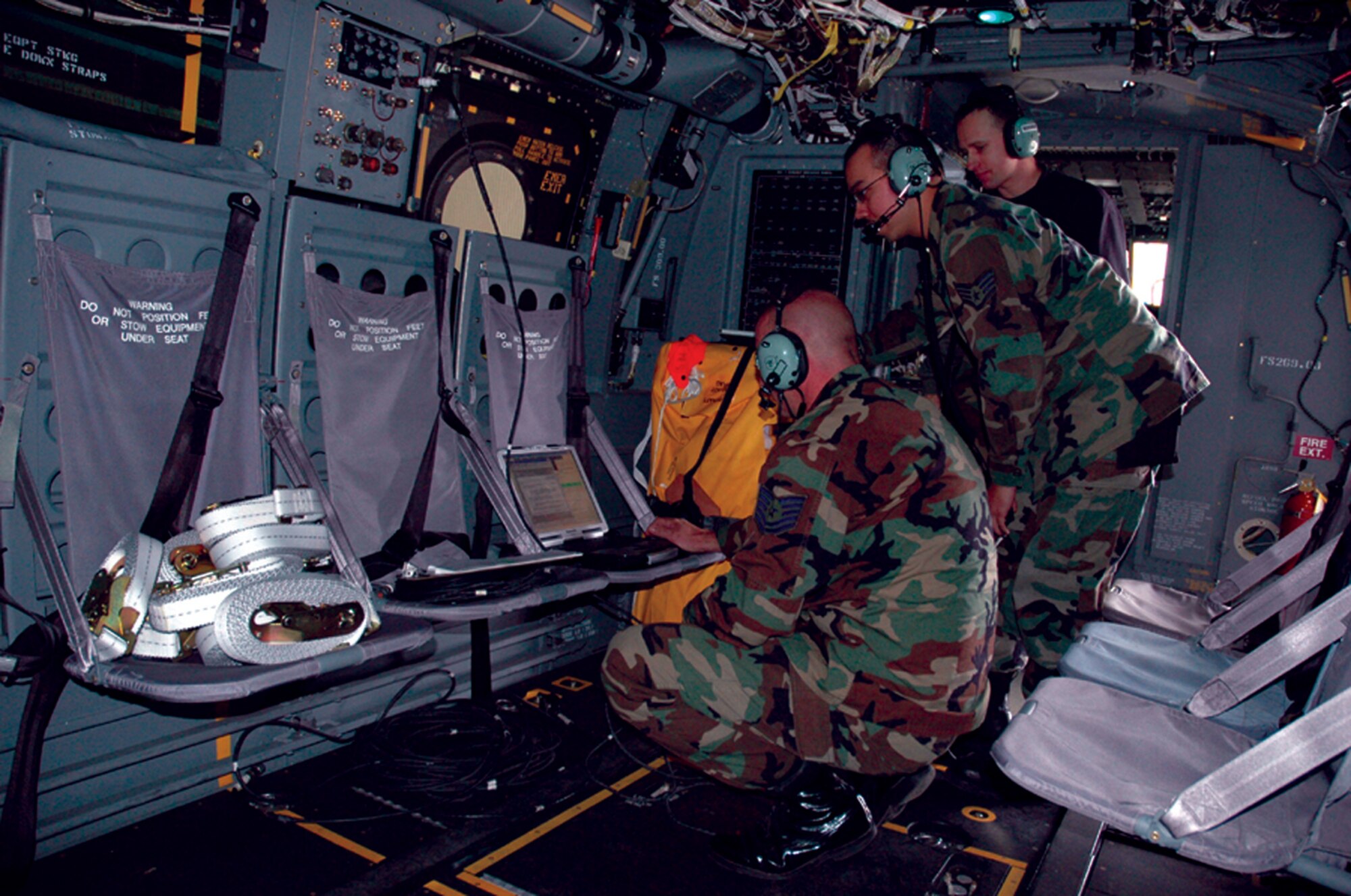Technical Sgt. Charles Reaves, left, and Staff Sgts. Jesse Marx, middle, and David Gilbert, 8th AMU maintainers, perform an aircraft software upload Friday, to the avionics systems aboard the CV-22. (U.S. Air Force Photograph by Jamie Haig)