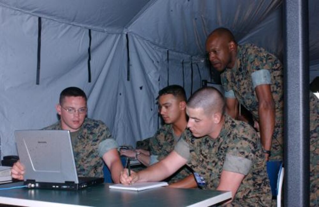 LAGER ALUENBACH, Germany -- U.S. Marine Corps Master Sgt. Kenneth Moore, technical controller from the 2nd Marine Expeditionary Force G6 looks over the shoulders of 8th Communications Battalion switch technicians Lance Cpl. Matthew Tiller, Sgt. Elisandro Patino and Lance Cpl. Isaac Holliday as they program the RSAM by loading groups of telephone communication channels or trunks April 27 during Combined Endeavor 2007. All are stationed at Camp Lejeune, N.C. Combined Endeavor 2007, a U.S. European Command-sponsored exercise, brings NATO, Partnership for Peace (PfP) and other nations together to plan and execute interoperability testing of command, control, communications and computer systems from participant nations in preparation for future combined humanitarian, peacekeeping and disaster relief operations.