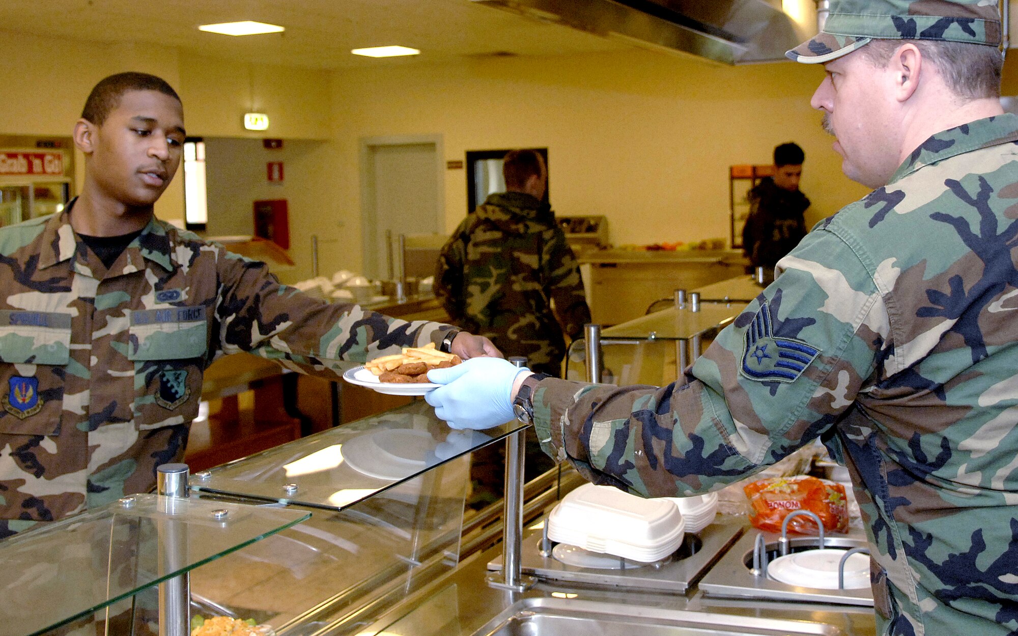 Staff Sgt. Troy Anderson serves lunch to an Airman at the La Dolce Vita Dining Facility Jan. 19 at Aviano Air Base, Italy. Sergeant Anderson is deployed to Aviano AB from the 121st Fighter Wing from Great Falls, Mont. Airmen at Aviano AB maintain two F-16 fighter squadrons to conduct regional and expeditionary operations under NATO, Supreme Allied Command Europe, or national tasking. (U.S. Air Force photo/Airman 1st Class Michael S. Dorus)
