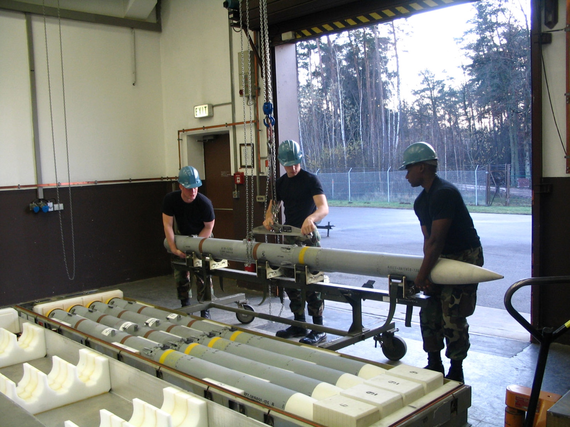 Missile maintainers prepare to remove the rocket motor from an older AIM-120A advanced medium-range air to air missile.  Removing the motor and placing it in a newer and more cabable AIM-120B or C model has saved the Air Force more than $31 million.  These Airmen are from the 435th Munitions Squadron at Ramstein Air Base, Germany.  (U.S. Air Force photo)