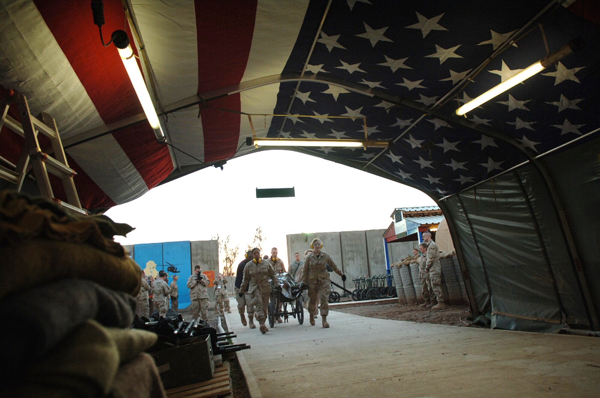 Airmen deployed to the 332nd Expeditionary Medical Group rush the first litter patient seeking medical treatment down Hero's Highway after posting the American flag Jan. 22 at Balad Air Base, Iraq. The flag is posted on the inner roof a tent so injured troops can look up and know they are in an American area when brought in on litters seeking medical treatment. The medical group raised injured troops' survival rate to 98 percent. (U. S. Air Force photo/Airman 1st Class Nathan Doza) 
