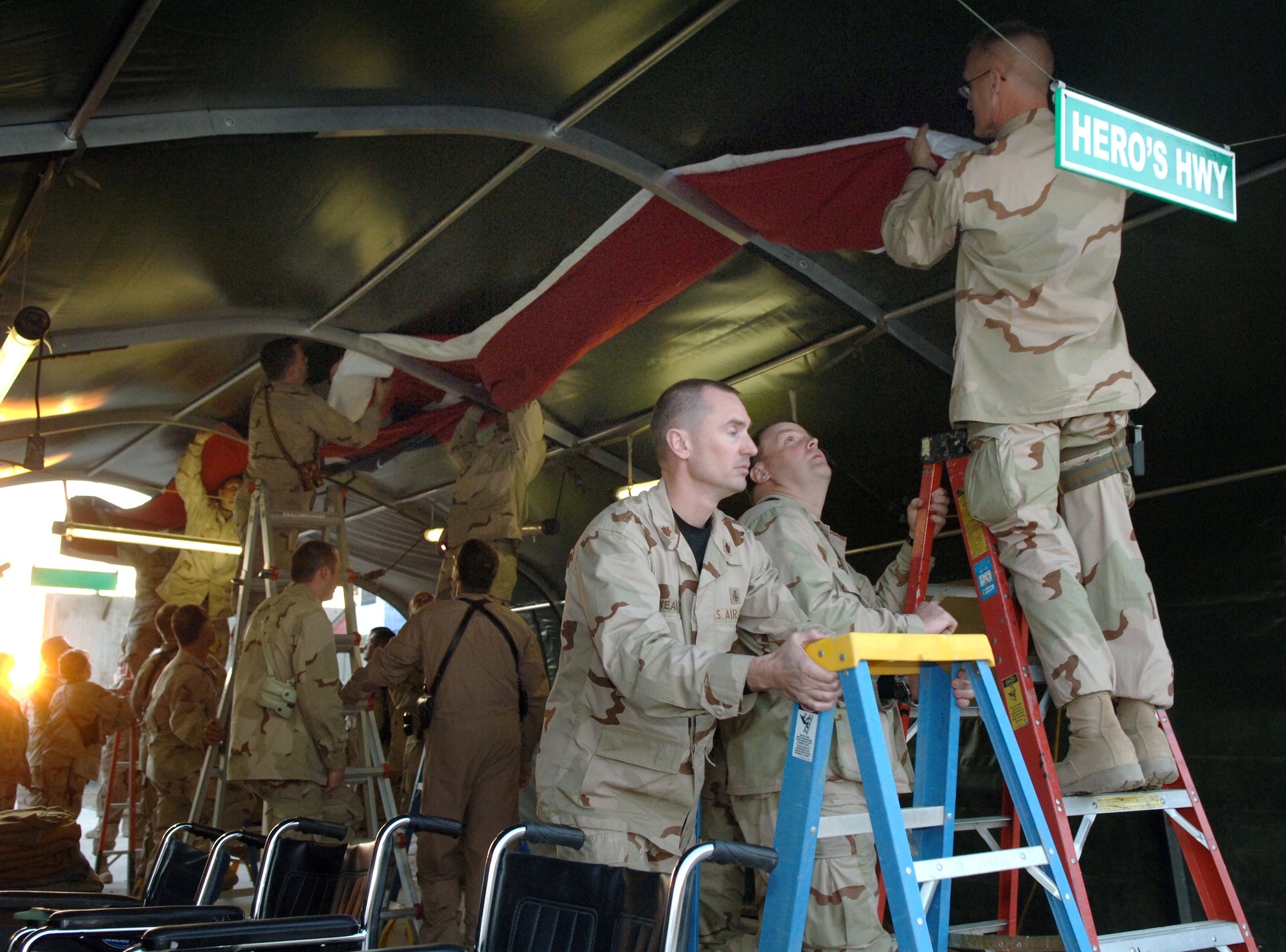 Airmen deployed to the 332nd Air Expeditionary Wing unfold an American flag at the Hero's Highway Ceremony Jan. 22 at Balad Air Base, Iraq. The flag is posted on the inner roof a tent so injured troops can look up and know they are in an American area when brought in on litters seeking medical treatment. The medical group raised injured troops' survival rate to 98 percent. (U. S. Air Force photo/Airman 1st Class Nathan Doza) 
