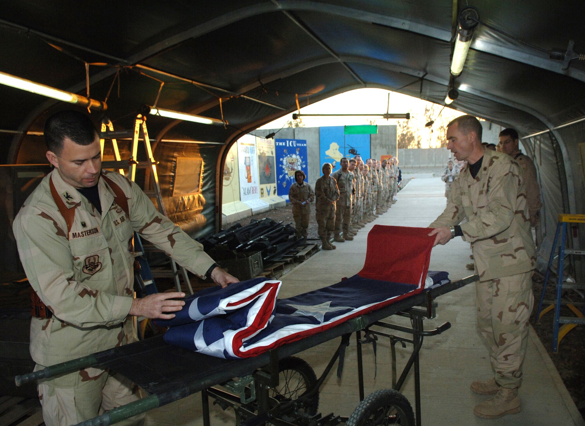 Col. Brian Masterson and Capt. Leslie McClain unfold an American flag at the Hero's Highway Ceremony Jan. 22 at Balad Air Base, Iraq. The flag is posted on the inner roof a tent so injured troops can look up and know they are in an American area when brought in on litters seeking medical treatment. The medical group raised injured troops' survival rate to 98 percent. Colonel Masterson is assigned to the 332nd Expeditionary Medical Group and Captain McClain is from the 332d Air Expeditionary Wing. (U. S. Air Force photo/Airman 1st Class Nathan Doza) 