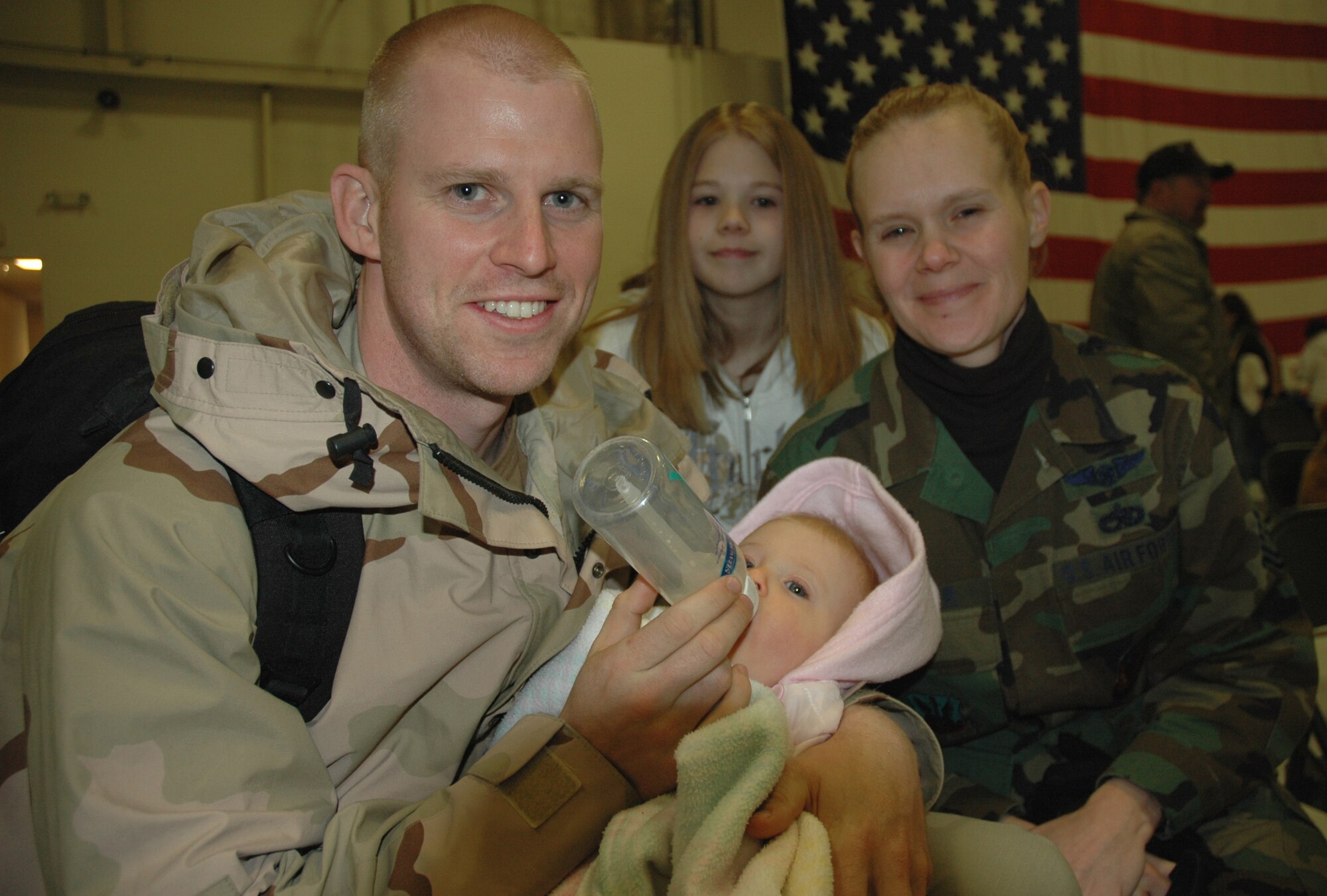 An Airman from the 726th Air Control Squadron feeds his newborn son for the first time since returning home from a four-month deployment Jan. 26.  More than 100 family members and friends piled into Hangar 1333 to greet to returning deployers who left in Sept. 2006.