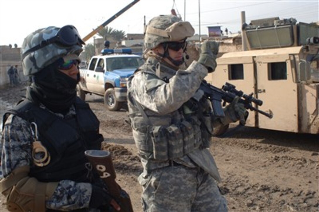 U.S. Army Staff Sgt. Maxwell Davis (right) and an Iraqi Policeman of 4th Brigade, 1st Iraqi National Police Division, provide security during a combined cordon and search mission in Baghdad, Iraq, on Jan. 16, 2007.  Davis is assigned to 2nd Infantry Division.  