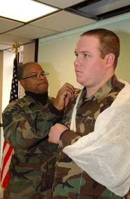 ANDREWS AIR FORCE BASE, Md. -- Tech Sgt. Phillip Williams ties an arm sling around Senior Airman Keith Riley's arm to demonstrate how to provide self-aid and buddy care in field conditions. (U.S. Air Force photo/Master Sgt. Shayne Sewell)