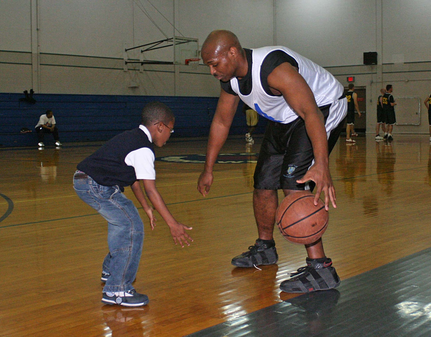 Angelo Baxter from the 314th Military Intelligence Battalion teaches dribbling to his son Elisha during half time Jan. 25 at the Chaparral Fitness Center. (Photo by Army Spc. Tim Luukkonen)
