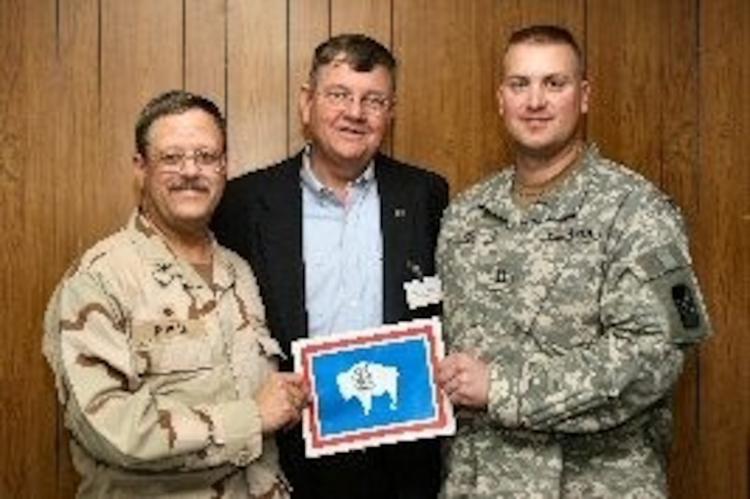 Wyoming Gov. Dave Freudenthal poses with Navy Reserve Capt. Stephen Nowak, left, and Army Capt. Michael Nack as they hold a picture of the Wyoming state flag at Camp Arifjan, Kuwait. Freudenthal is among four state governors visiting troops from their states in the region this week. Photo courtesy Wyoming Governor's Office