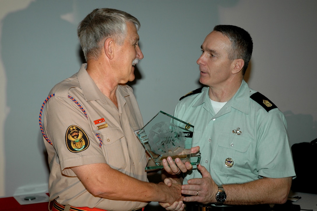 Army Command Sgt. Maj. William J. Gainey (right), senior enlisted advisor to the chairman of the Joint Chiefs of Staff, presents a gift to Warrant Officer 1 Jakes Jacobs, warrant officer of the South African National Defense Force, Feb. 10 at the conclusion of the International Warrant Officers Conference at Tempe Military Base, in Bloemfontein, South Africa. Jacobs hosted the conference of about 50 senior noncommissioned officers from around 20 countries. South Africa and many other countries use the term "warrant officer" to describe senior noncommissioned officers, roughly equivalent to pay grades E-7 to E-9 in the U.S. military services. Photo by South African Air Force Sgt. Heinrich Louw