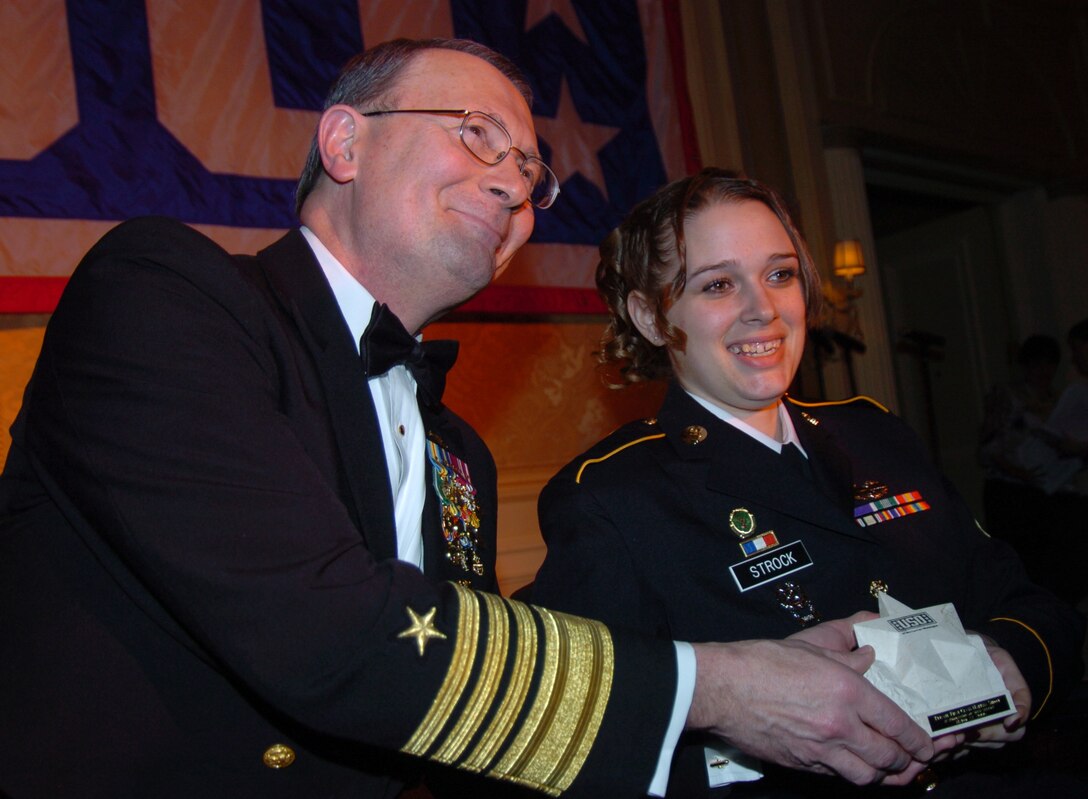 Navy Adm. Edmund Giambastiani, vice chairman of the Joint Chiefs of Staff, presents Army Pfc. Marissa Strock with a USO award for her service in Iraq. The admiral presented seven USO awards to servicemembers from every branch, including the Coast Guard, during USO of Metropolitan Washington annual awards dinner, March 22. Photo by Tech. Sgt. Sean P. Houlihan, USAF