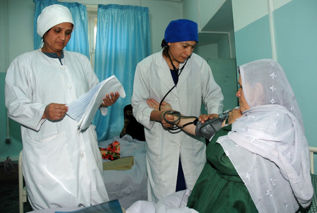 Meena Rasooli (left) an obstetrician-gynecologist for the Rabia Balkhi Maternity Hospital, examines a patient's chart while Jamila, a midwife, checks her blood pressure at the hospital in Kabul, Afghanistan, April 9. The U.S. departments of Defense and Health and Human Services invested a combined $10 million into renovations, then presented the hospital to Afghanistan's minister of public health in a formal ceremony April 9. Photo by Staff Sgt. Benjamin Rojek, USAF
