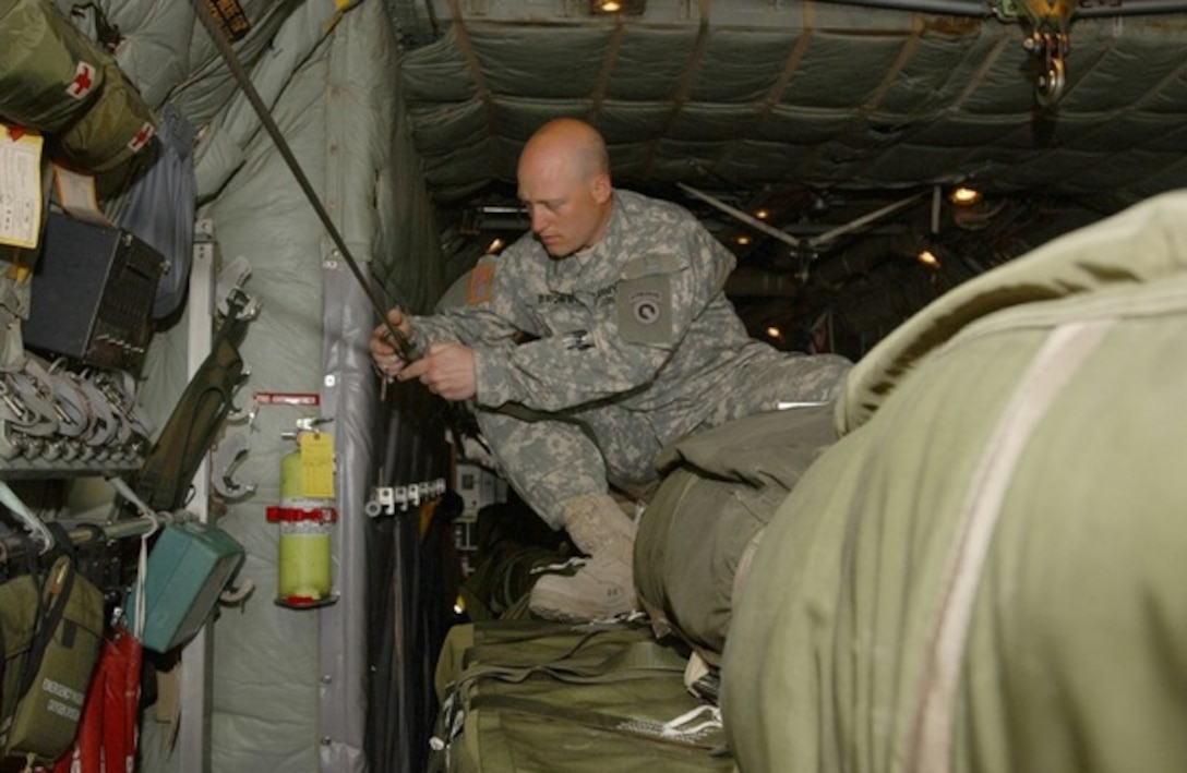 A Green Beret assigned to 1st Battalion, 10th Special Forces Group  (Airborne), attaches the snap hook of his universal static line to the  anchor-line cable of a C-130 Hercules mock-up during pre-jump