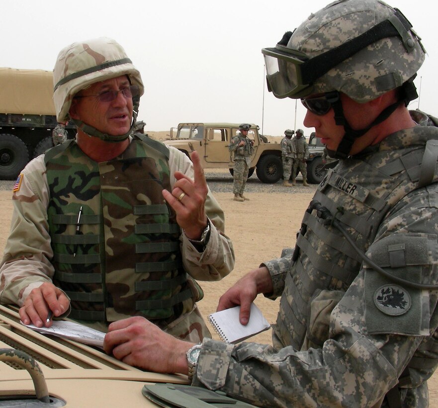 An operational expert from Military Professional Resources Inc., a contractor that runs Udairi Range, in Kuwait, to train U.S. forces heading into Iraq, makes a point to convoy commander Army Staff Sgt. Matthew Miller during live-fire exercises in the Kuwaiti desert. Miller, with the 1st Battalion, 214th Field Artillery Regiment, said he learned a lot from the training exercise. Photo by Jim Garamone