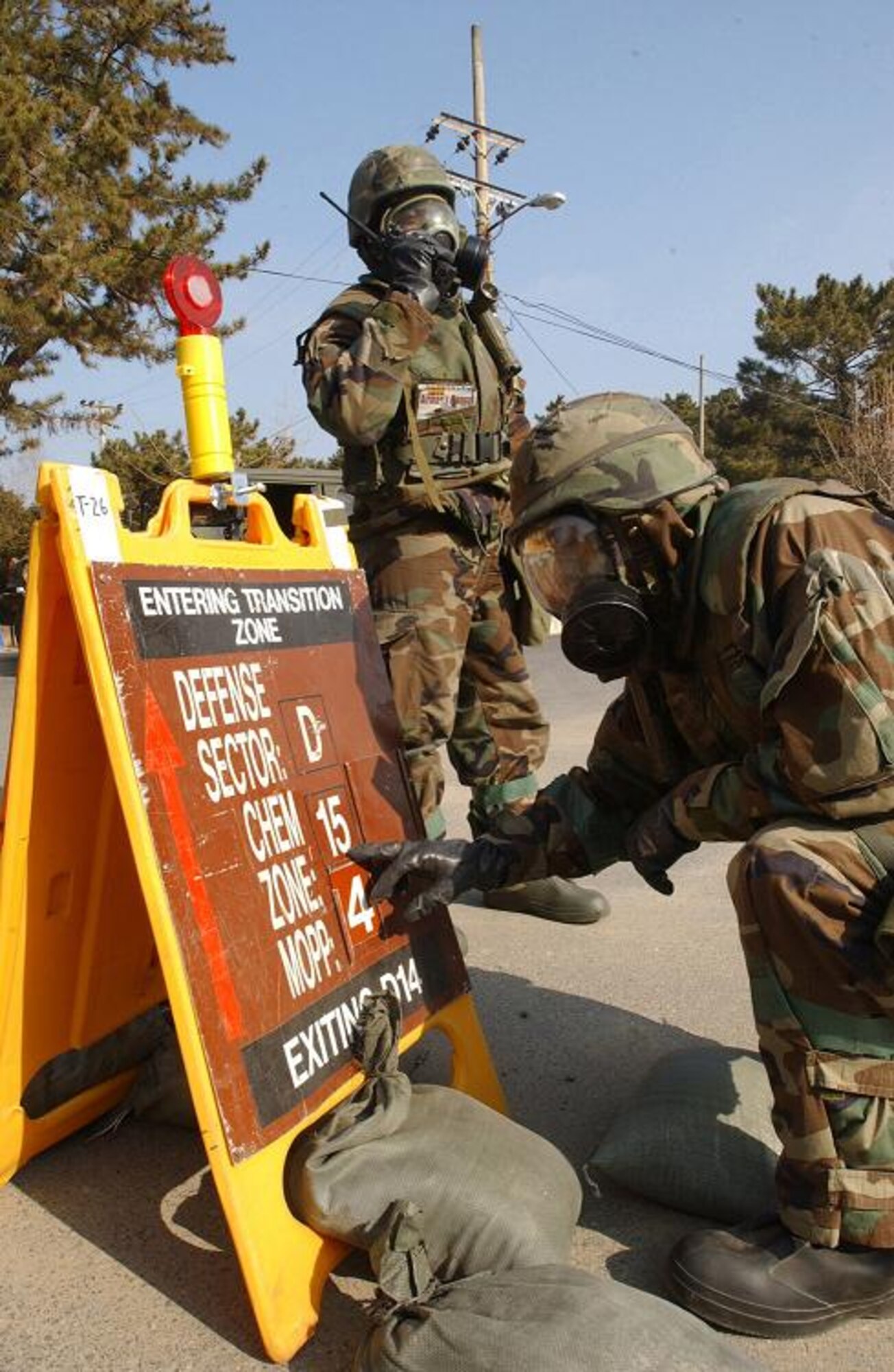 Airman 1st Class Bernard Byer (left) radios in his chemical reconnaisance team's report as Senior Airman Melvin Lucas changes a zone transition point sign during the first peninsula-wide combat employment readiness exercise, or PENCERE of the year. 'ZTP' signs inform other Airmen what sectors they are enter and whether that sector is contaminated with biological or chemical agents. Both Airmen are assigned to the 8th Communications Squadron. (U.S. Air Force photo/SrA Stephen Collier)                             