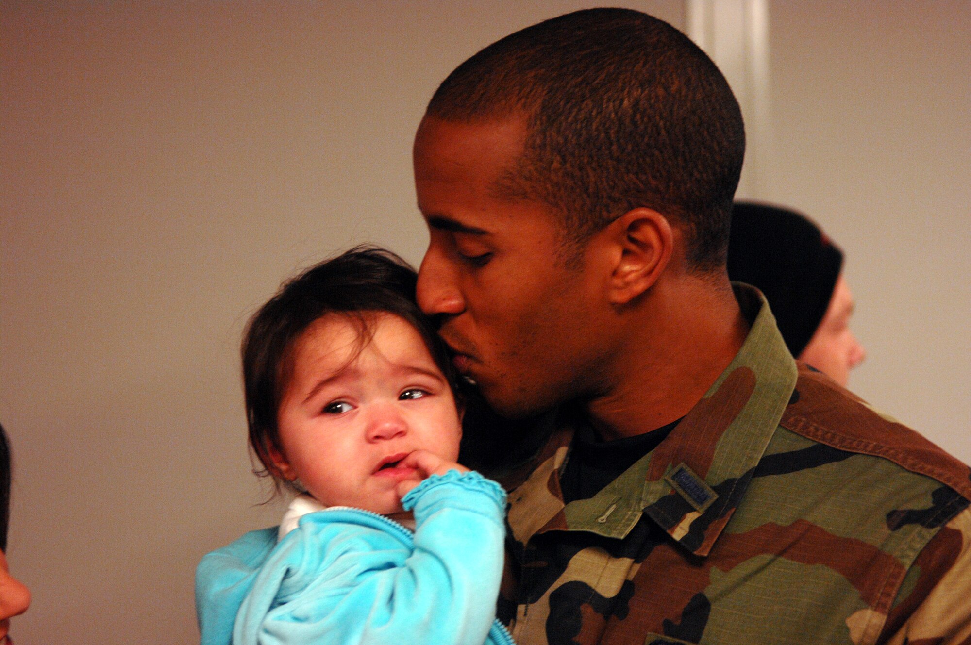 MINOT AIR FORCE BASE, N.D. -- First Lt. Dwayne Clark, 23rd Bomb Squadron, kisses his daughter Mikaila after returning from a deployment Jan. 30. Lieutenant Clark and 109 other Minot Airmen were met by friends and family upon arriving home from a five-month deployment to Andersen Air Force Base, Guam. (U.S. Air Force photo by Airman 1st Class Christopher Boitz) 