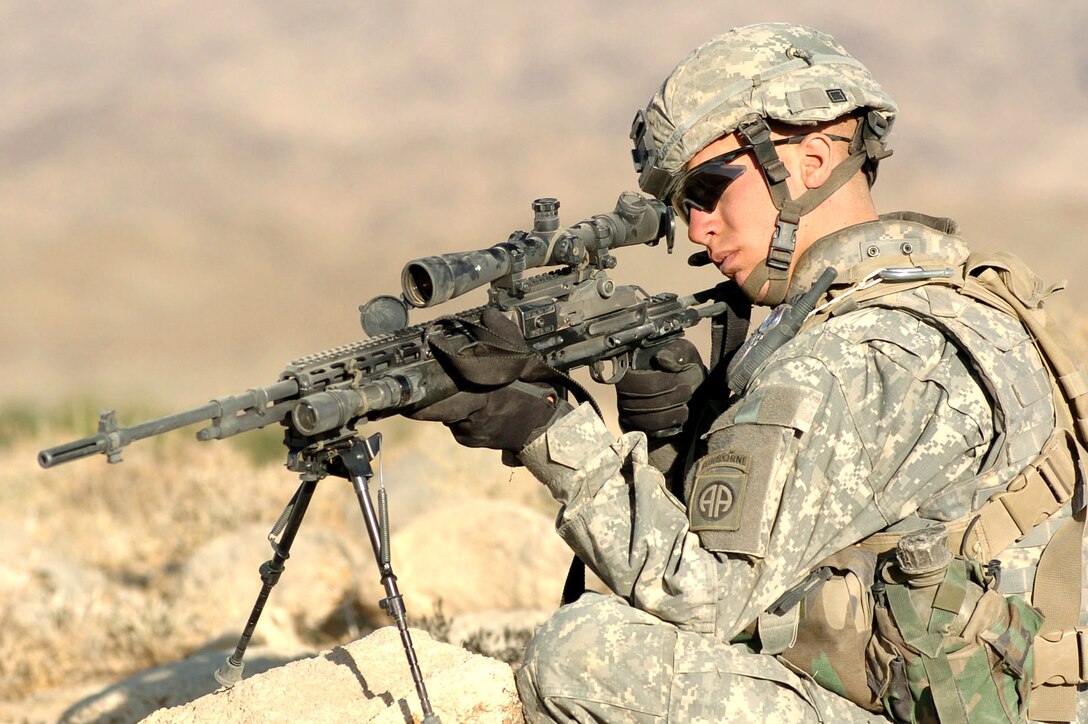 Army Spc. Ronald Turner provides "overwatch" protection from atop a hill while other members of his platoon search a village in Mianashin, Afghanistan, Oct. 1. Photo by Spc. Mike Pryor, USA