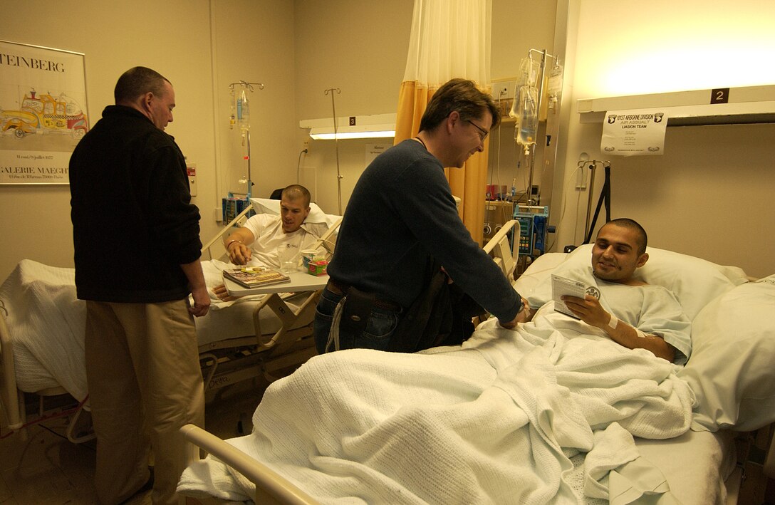 Kevin Bernzott (left) and Kevin Roberts, of the Department of Defense's Joint Civilian Orientation Conference, visit with an injured soldier and Marine at Landstuhl Regional Medical Center, Germany, on Oct. 19. The two, along with other JCOC members, brought phone cards totaling more than 25,000 minutes and dozens of DVDs and CDs to wounded servicemembers. JCOC is a weeklong, multiservice orientation for civilian public opinion leaders. Participants start their orientation with briefings from senior Pentagon leaders and then travel to various U.S. military locations around the world. Photo by Staff Sgt. Suzanne M. Day, USAF