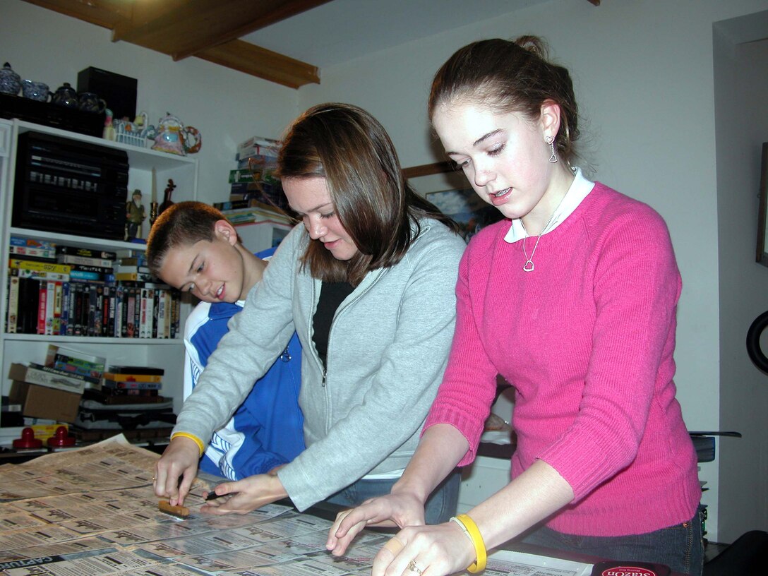 Robbie, Courtney and Brittany Bergquist prepare prepaid phone cards in the basement of their family's Norwell, Mass., home last year for delivery to a unit deploying to Iraq. The Defense Department's Contracting Center of Excellence has been collecting donations this holiday season for the Bergquist children's "Cell Phones for Soldiers" program. Photo by John D. Banusiewicz