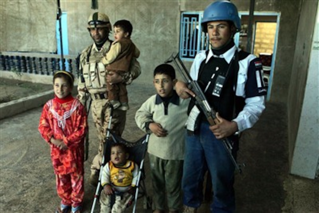 An Iraqi soldier with the Iraqi Army’s 2nd Battalion, 1st Brigade, 7th Division, and a policeman from the 17th Street Security Station Police Detachment pose for photos with local Iraqi children during a joint patrol in the Thaylat District of Ar Ramadi, Iraq, on Jan. 24.