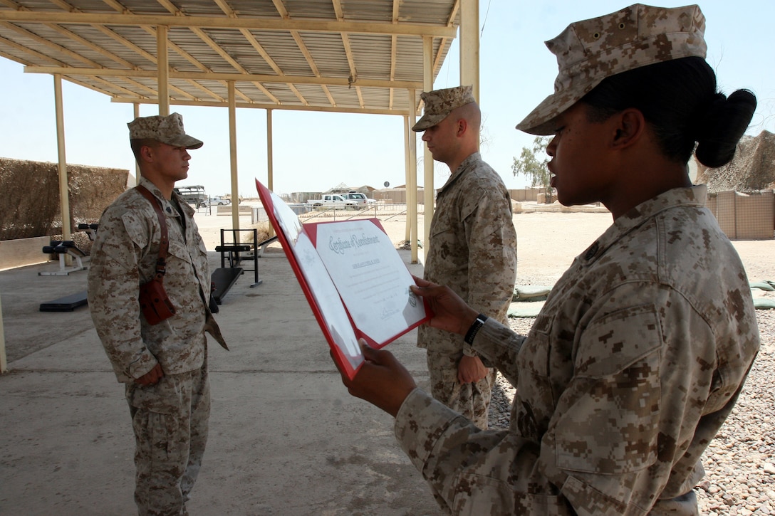 AL TAQADDUM, Iraq (July 2, 2007) ? Sgt. Cyril K. Enos and 1st Lt. Jason M. Carberry stand at attention as Staff Sgt. Renaunda G. Davis reads Enos? Certificate of Reenlistment near the chapel here July 2.  More than 30 Marines from the 2nd Marine Logistics Group (Forward) have reenlisted since arriving here more than five months ago.  Enos is the noncommissioned officer-in-charge of the armory, a landing support specialist and Makaha, Hawaii, native with Headquarters Company, 2nd MLG (Fwd).  Davis is the career retention specialist for Headquarters, Service and Communication Companies, 2nd MLG (Fwd).