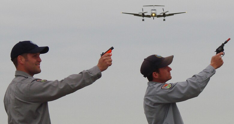 Wildlife Services biological science technicians Jesse Townsend(left) and Matt Smith, from the U.S. Department of Agriculture, prepare to fire pyotechnics to scare away geese and other birds that like to make the farming area around Vance AFB, Okla., their private "buffet." Dispersing the birds to other locations makes flying safer for aircraft such as the BE-20 (right) (Photo by 2nd Lt. James Justice)