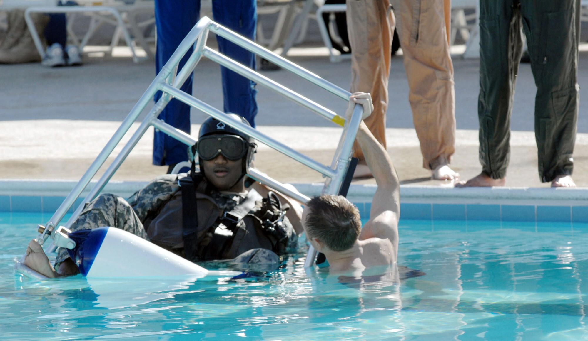 Staff Sgt. Michael Nettleingham instructs Army Staff Sgt. Joe Mangram on helicopter escape procedures in the event of a water landing.  Sergeant Nettleingham is a survival, evasion, resistance and escape, or SERE, instructor at Nellis Air Force Base, Nev.  Sergeant Mangram, a Nevada Army National Guardsman, was taking his annual water survival training.  (U.S. Air Force photo/Master Sgt. Kevin J. Gruenwald)