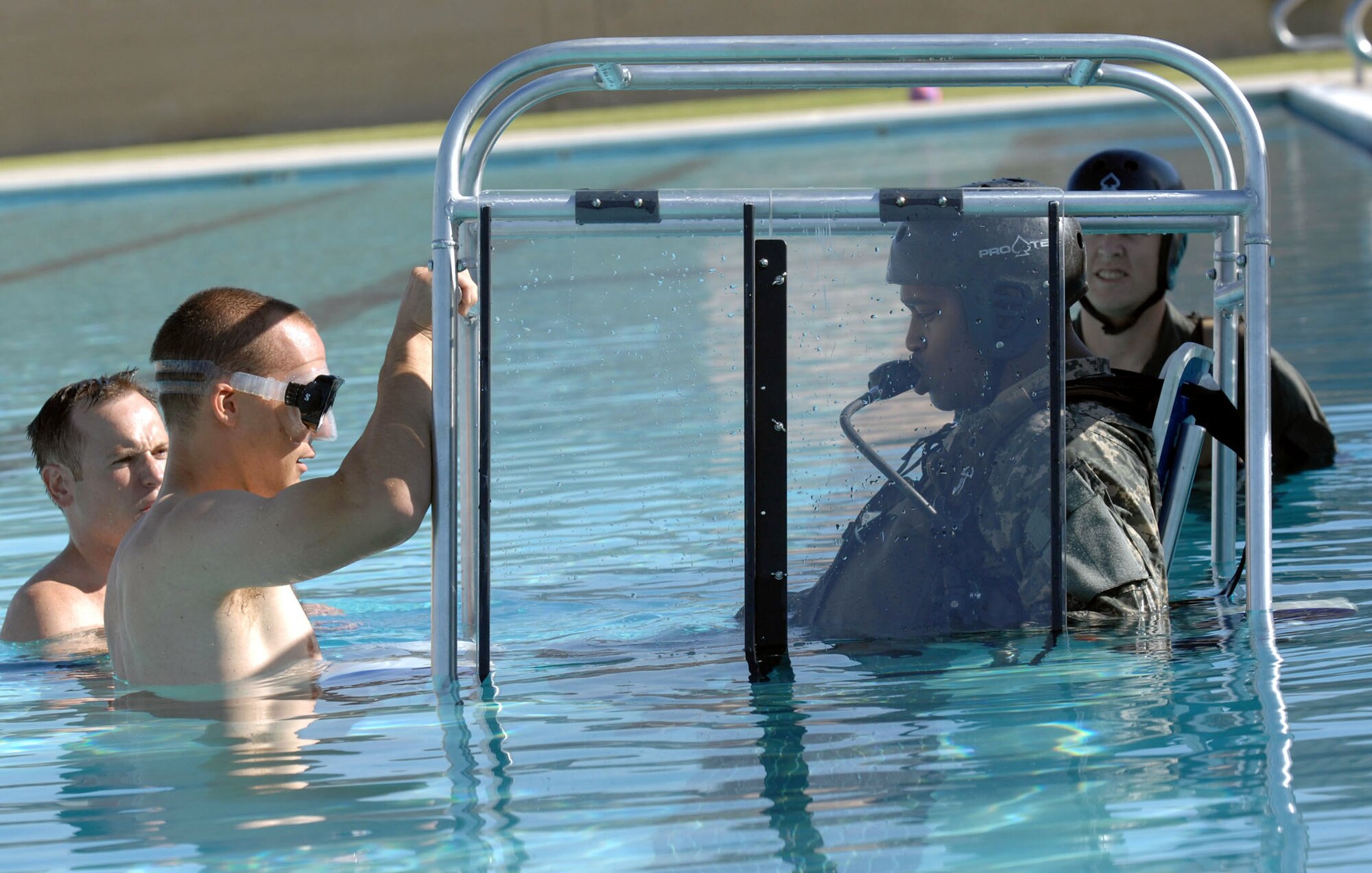 Staff Sgt. Chris Jones (in goggles) and Staff Sgt. Michael Nettleingham instruct Army Staff Sgt. Joe Mangram on helicopter escape procedures in the event of a water landing.  The sergeants are survival, evasion, resistance and escape, or SERE, instructors at Nellis Air Force Base, Nev.  Sergeant Mangram, a Nevada Army National Guardsman, was taking his annual water survival training.  (U.S. Air Force photo/Master Sgt. Kevin J. Gruenwald)