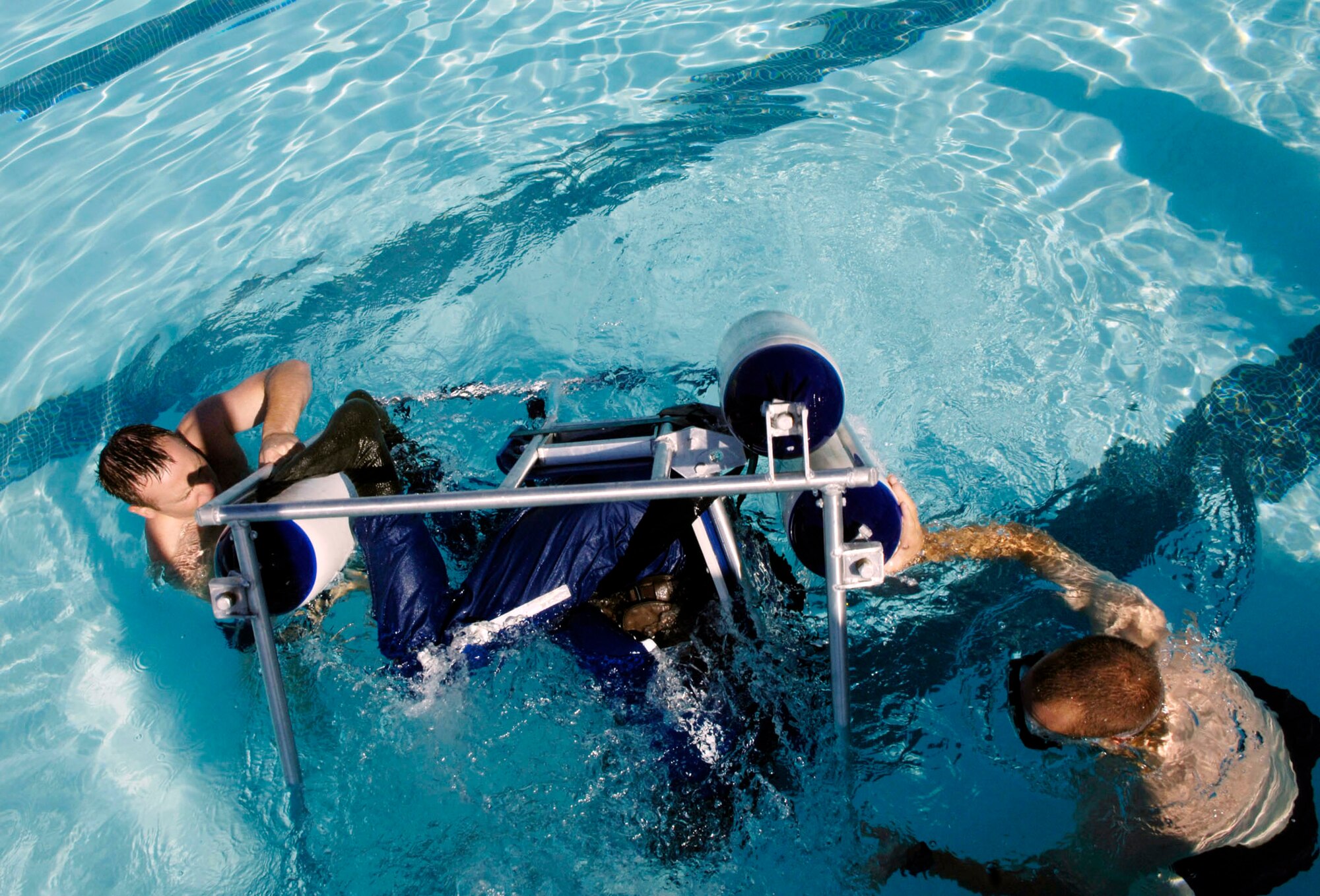 Staff Sgt. Michael Nettleingham (left) and Staff Sgt. Chris Jones train Army Chief Warrant Officer James Mininger on helicopter escape procedures in the event of a water landing.  The sergeants are survival, evasion, resistance and escape, or SERE, instructors at Nellis Air Force Base, Nev.  The Army National Guardsmen, an OH-58 Scout pilot, was taking his annual water survival training.  (U.S. Air Force photo/Master Sgt. Kevin J. Gruenwald)
