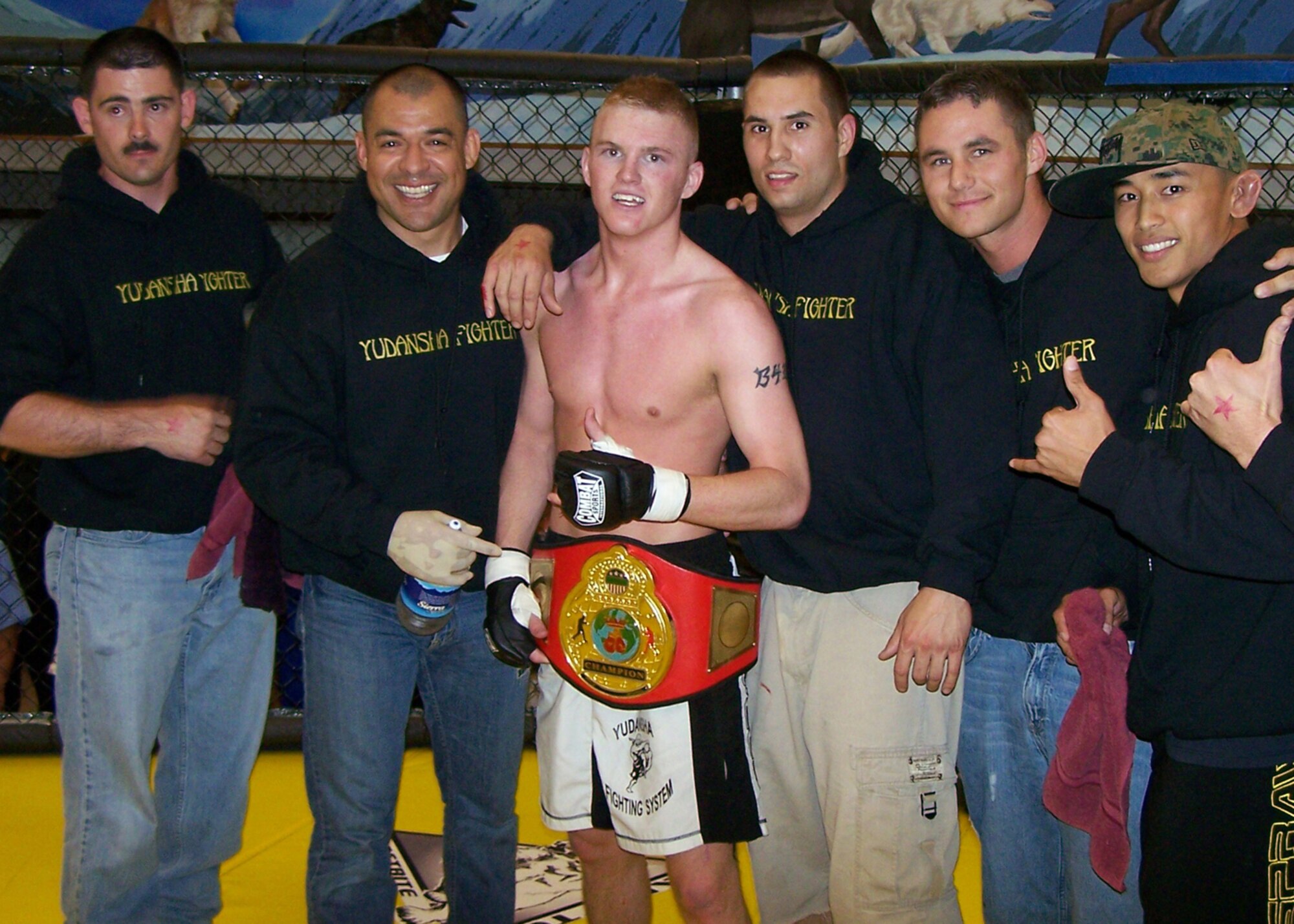 EIELSON AIR FORCE BASE, Alaska--Brett Laswell (center), an Airman with the 354th Maintenance Squadron, poses with team mates after defeating reigning bantam weight title holder Jeff Baily of Fairbanks' Gladiators Mixed Martial Arts team with a reverse arm bar two minutes and 45 seconds into the first round June 22. Laswell?s victory brings his record to 3-0 since he began competing in March of this year. (courtesy photo)