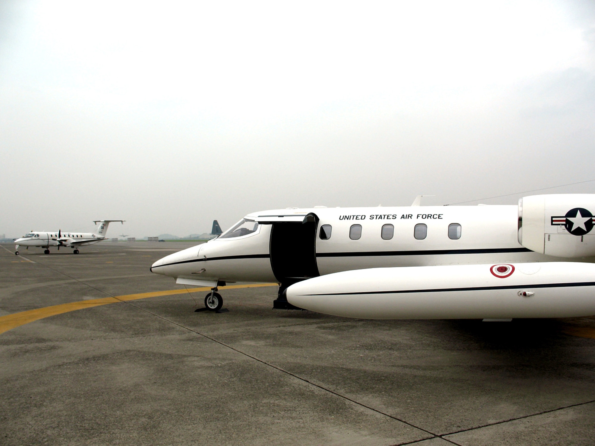 The C-12J Huron (left) arrives as the C-21 transport jet prepares to leave after serving for 21 years June 29 on Yokota Air Base, Japan. The C-12 is roomier than its predecessor, and has the ability to carry more people and land in more remote areas. (U.S. Air Force photo/Navy Seaman A.C. Rainey)