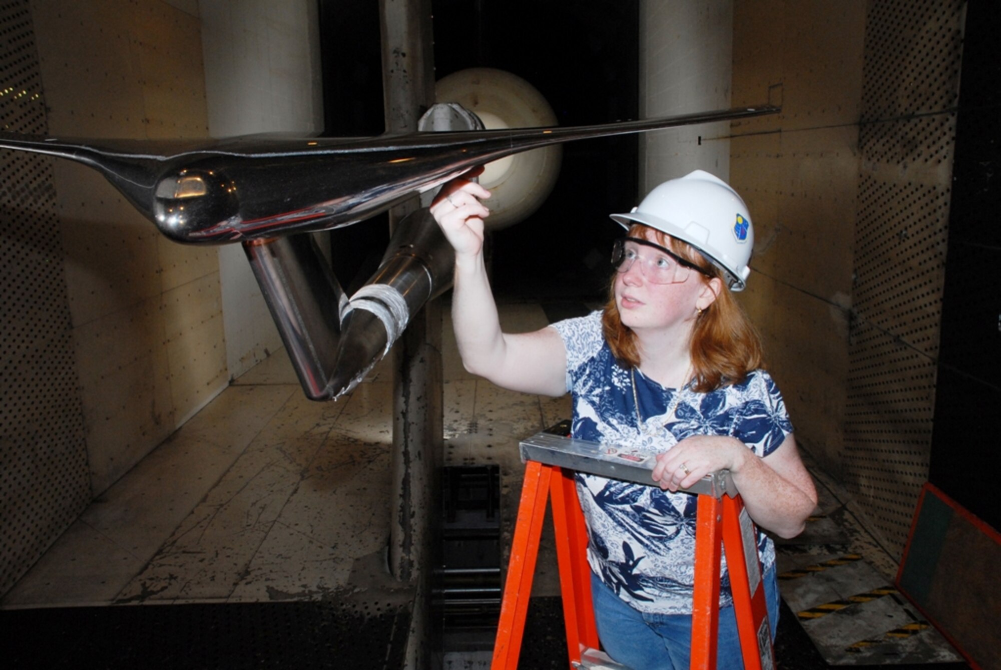 NASA Research Engineer Melissa Carter inspects the Blended Wing Body concept test article during a model change before resumption of aerodynamic testing in AEDC’s 16-foot transonic wind tunnel. (Photo by David Housch)